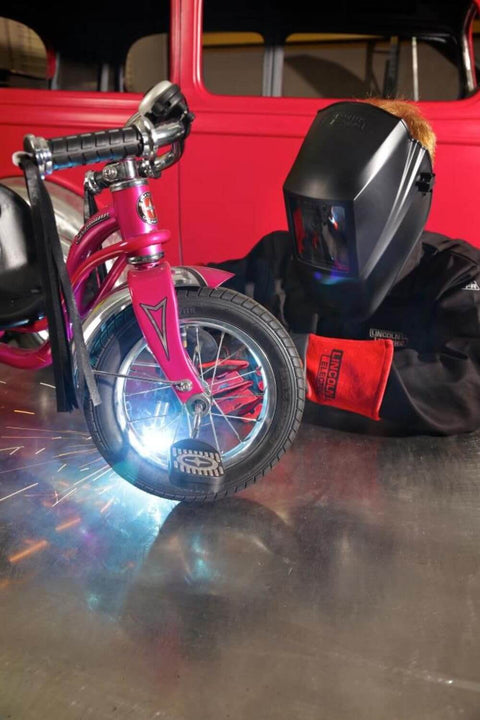 Person welding a bicycle while wearing K2800-1 4.5 By 5.25 Inch Auto Darkening Weld Helmet With Grade Ten Lens ANSI Certified helmet.