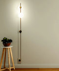 Equinox LED Wall Sconce Indoor Plug In Light For Bedroom And Bathroom With Glass Globe Shades Industrial Wall Mounted Fixture And On Off Switch Gold Finish Perfect For A Modern Home Vibe, shown illuminated on a wall with a side table.