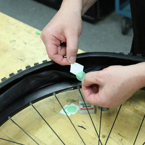 Hands using Bike Tire Patch Kit With Peel And Stick Patches And Extra Tough Tire Levers, Built In Sealant Inner Tubes That Stop Flats