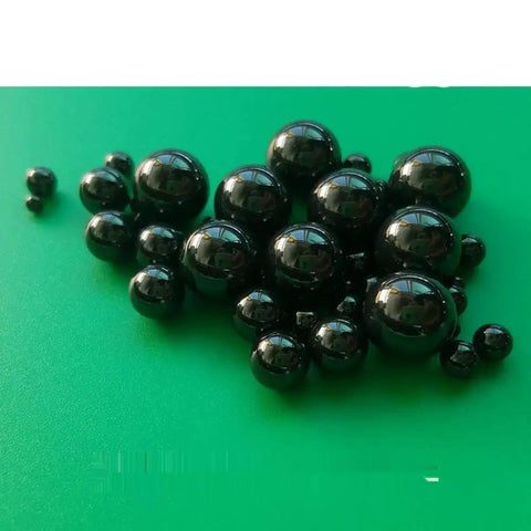 Twenty Piece Lot Of 1.588Mm Silicon Nitride Ceramic Balls G5 Grade on a green background, showcasing various sizes of black ceramic balls.