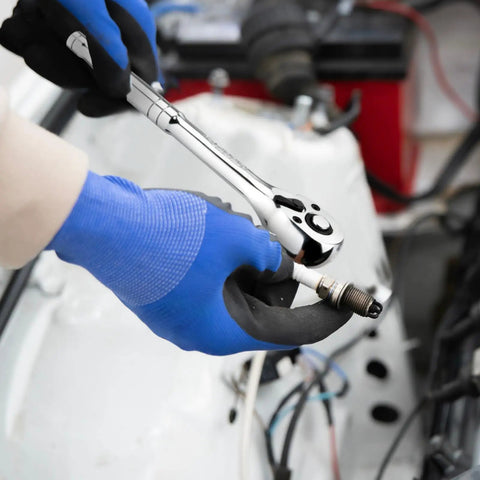 Close-up of a gloved hand using a ratchet handle from the 12 Piece Spark Plug Socket Set With 3/8 Inch Drive on a spark plug.