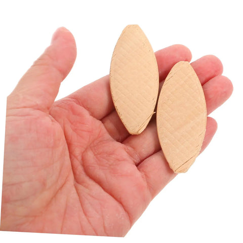 Hand holding two light yellow joining biscuits from 100Pcs Wood Joining Biscuits Set For Rock Solid Furniture Joints Hardwood Joiner Accessories