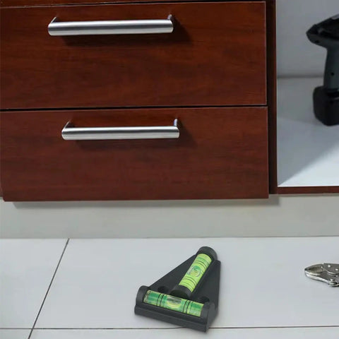 T Shaped Horizontal Bubble Level 2 Way For Spirit Level With Fluorescent on tiled floor near wooden cabinets.