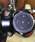 Close-up of wireless Bluetooth car media button with steering wheel remote easy music play pause skip volume control works with iOS and Android car kit receiver CR2032 battery included, mounted on handlebars.