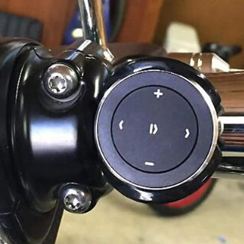 Close-up of wireless Bluetooth car media button with steering wheel remote easy music play pause skip volume control works with iOS and Android car kit receiver CR2032 battery included, mounted on handlebars.