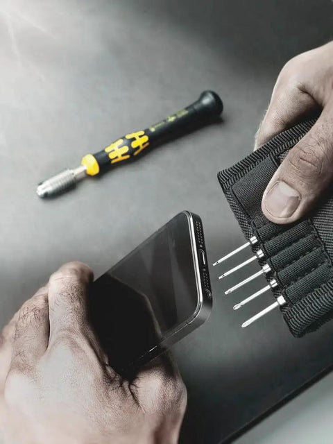 Hands using Kraftform Kompakt ESD 11 Piece Micro Tool Set For Precision Mechanics with smartphone and tool bits visible.