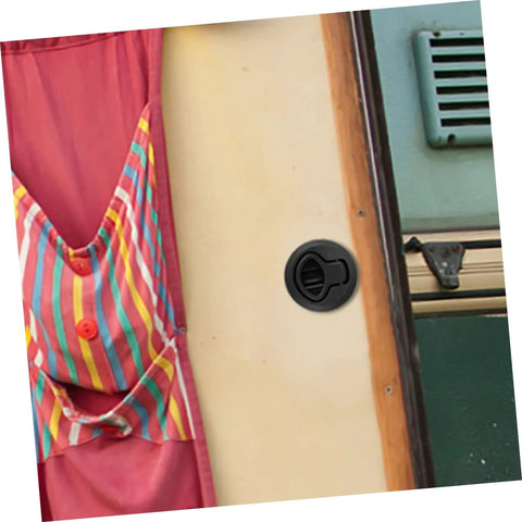 Black flush-pull slam latch on boat cabin wall with a round recessed handle.
