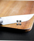 Boss Grade Stainless Steel Knife Handle Screws With Locking Spindle Pins Two Pack on wooden cutting board next to knife.