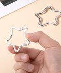 Hand holding one of the Two Pack Aluminum Star Shaped Carabiners With Key Rings, Small Silver Snap Hooks for Keys and Wallets.