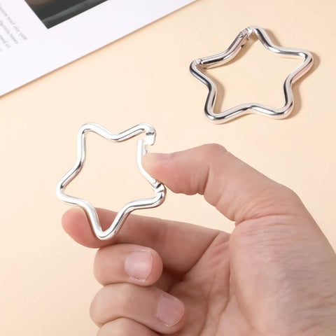Hand holding one of the Two Pack Aluminum Star Shaped Carabiners With Key Rings, Small Silver Snap Hooks for Keys and Wallets.