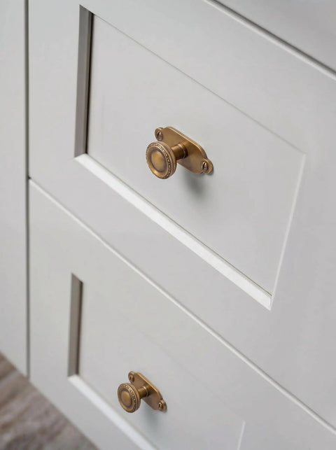 Top Notch Heavy Duty Solid Zinc Cabinet Knobs With Vintage Oval Beaded Back Plates Antique Brass Finish Six Pack displayed on white drawers.