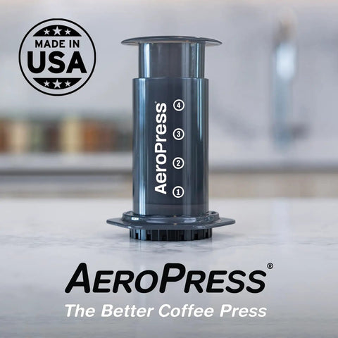 Aeropress coffee maker shown on a kitchen countertop, featuring plunger and chamber, USA made, compact and portable design.