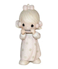 Figurine of a girl in a pink dress playing harmonica with flower patterns and a bow in her hair.