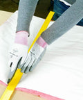 Person cutting R8 Fiberglass Garage Door Insulation Kit fits nine foot entries with a utility knife on a workstation.