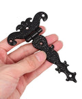 Hand holding vintage style black zinc alloy tee door hinge, slip joint lift off, for cabinets and sheds, 2 pack shown.