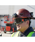 Worker wearing tinted safety goggles with anti-fog lens for pro grade eye protection, scratch resistant UV shield, adjustable vents, ANSI Z87.1 Plus.