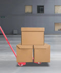 Heavy Duty Three Wheel Machinery Mover Dolly Handling Two Ton Loads With Grippy Swivel Handle And Rock Solid Pu Caster Wheels moving stacked cardboard boxes.
