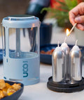 Red Candle Lantern For Camping And Emergencies with aluminum build shown next to three nine-hour emergency candles being lit.