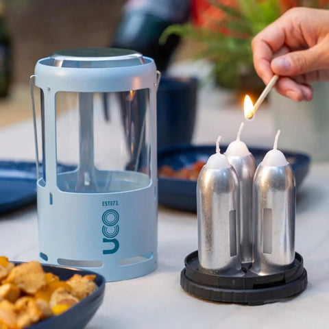Red Candle Lantern For Camping And Emergencies with aluminum build shown next to three nine-hour emergency candles being lit.