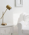 Desk Lamp In Matte Brass Finish With Adjustable Height And Balance Arm Inline Rocker Switch next to white armchair