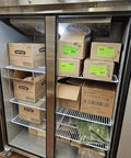 Inside view of Heavy Duty Commercial Upright Freezer Stainless Steel Two Door Reach In Cooler 36 Cubic Foot Capacity with packed boxes and herbs.