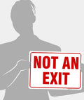 Built Tough Premium Aluminum Sign For Indoor And Outdoor Use No Fuss Rust Free Weatherproof And Ultra Durable With A Sharp Professional Look For Home Office Garage Shop And Retail Spaces. "NOT AN EXIT" sign held by person