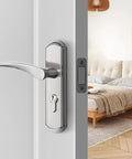 Modern bedroom interior with silver door handle and lock on a white door, partially open to reveal a cozy bed and decorative lamp.