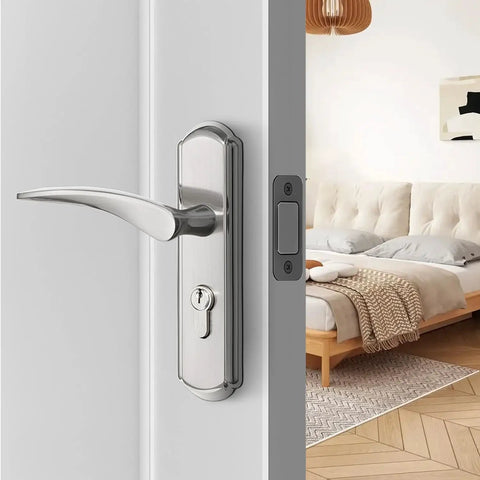 Modern bedroom interior with silver door handle and lock on a white door, partially open to reveal a cozy bed and decorative lamp.