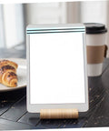 Tablet stand on table with croissant and coffee cup in background