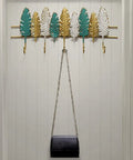 Heavy Duty Wall Mounted Coat Rack For Entryway And Office Straight Up Sturdy Iron Build with leaf design holding bags.