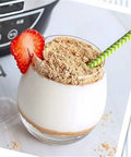 Delicious yogurt topped with crushed graham crackers and a strawberry, served in a clear glass for a healthy treat.