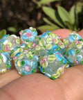 Score These Hella Rad Lampwork Glass Round Spacer Beads With Big Center Holes Perfect For DIY Jewelry Making Kicking Up Your Bracelet And Necklace Crafting Vibes Today, assorted blue and green floral beads in hand.