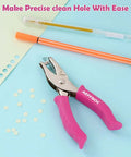 One Hole Punch With Soft Grip Handle For Paper One Quarter Inch Hole Punch Pink With Mess Tray Six Sheet Capacity Ideal For Crafts And Scrapbooks Great For DIY Projects on a blue background with pens and punched paper circles.