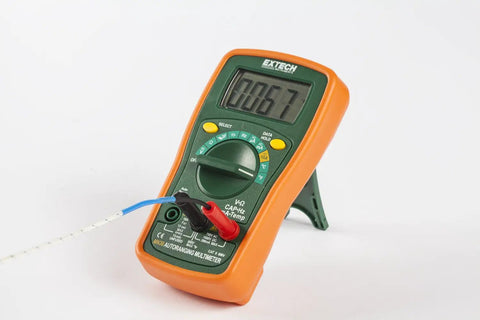 MiniTec Autoranging Digital Multimeter With 600V AC DC, 10A Current, Temperature, Resistance, Capacitance, Frequency, Continuity And Diode Testing, Includes Protective Holster And Tilt Stand in orange protective holster.