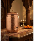 Copper Water Dispenser With Hammered Finish and Joint Free Body, Brass Stand and Tap, 5 Liter Capacity on ornate table