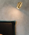Top Tier Brass Wall Sconce With G4 Socket, Modern Bedside And Hallway Light illuminating a dark wall above a bed.