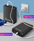 Portable metal power bank with USB and Type-C charging ports connected to phone and wall socket.