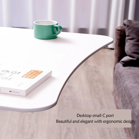 Mobile Standing Desk With Pneumatic Height Adjustment Rolling Sit Stand Cart Riser Low Profile Couch Bed Desk Smooth Roll Home Office Studio Podium Wide Work Surface with green cup and book on white top.