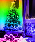 150ft RGB LED Strip Lights With App Control And Remote illuminating a Christmas tree and room with color-changing mood lighting