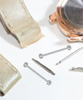 Two Pack Screw In Metal Watch Band Pins 0.98 X 0.15 Inch Replacement Link Rods next to watch components.