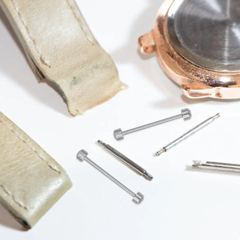 Two Pack Screw In Metal Watch Band Pins 0.98 X 0.15 Inch Replacement Link Rods next to watch components.