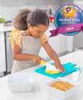 Kids' cutting set for toddlers; child uses a safety knife on a turquoise cutting board in a kitchen.