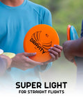 Person holding orange disc from Gravity Disc Golf Starter Set with Pure Fuse Explorer Saint Diamond Bolt, lightweight plastic for beginners.
