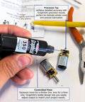 Hand holding a 15ml bottle labeled 'Graphisi 350 cSt', with precision nozzle near small gears and tools, on a workshop table.