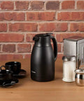 Stainless Vacuum Carafe 1.5 Liter Matte Black With Extra Wide Two And One Half Inch Mouth on table with cups