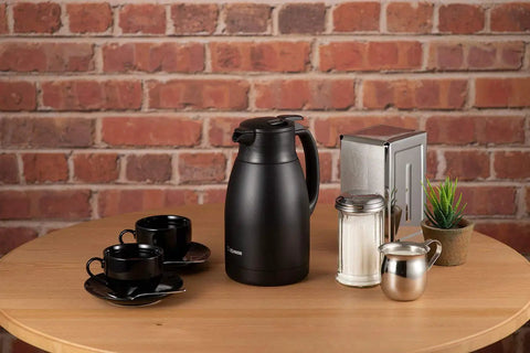 Stainless Vacuum Carafe 1.5 Liter Matte Black With Extra Wide Two And One Half Inch Mouth on table with cups