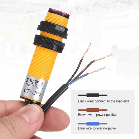 Close-up of a yellow Dual Through Beam Photoelectric Sensor, M18 size, wires for power connections, used in industrial automation.