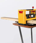 Rock Solid Bench Top Thickness Planer Delivering Beasty 2000W Power For Killer Smooth Cuts And Fast Wood Stock Reduction on a table, with a wooden board feeding through.