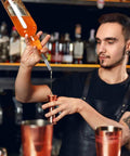 Set Of 2 Stainless Steel Pourers For Liquor Olive Oil And Vinegar Bottles With Tapered Stopper Spouts No Spill Control Sealed Dust Caps Fits About Three Quarters Inch Bottle Openings Durable And Easy To Clean Built Like A Tank. bartender pouring liquor with stainless steel pourer into a jigger