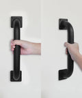 Heavy Duty 12 Inch Square Matte Black Staircase Handrails In A Two Pack Feature Solid Steel Construction For Indoor And Outdoor Step Support With Wall Mount Safety Grab Bars And Smooth Gate Handles Built Like A Damn Tank To Catch You Securely On Slippery, showing hand gripping a sturdy matte black handrail.